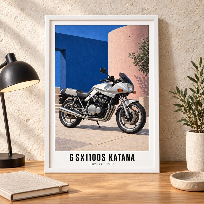 Puede incluir: Una impresi&oacute;n art&iacute;stica enmarcada que muestra una motocicleta Suzuki GSX1100S Katana plateada de 1981 estacionada sobre una superficie pavimentada frente a paredes arquitect&oacute;nicas azules y rosas. El texto GSX1100S KATANA Suzuki 1981 aparece abajo.