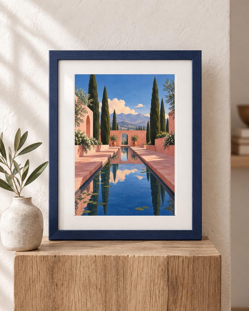 Pu&ograve; includere: Una stampa artistica incorniciata che raffigura un paesaggio in stile mediterraneo con una lunga piscina riflettente rettangolare, alti cipressi e pareti in stucco rosa sotto un cielo azzurro con montagne, in una cornice di legno blu scuro.