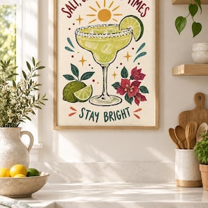 May include: A framed wall art print featuring a margarita in a glass with a salted rim, a lime wedge, and ice cubes. The text reads SALT, CITRUS, GOOD TIMES and STAY BRIGHT. The illustration includes a sun, lime fruit, and pink flowers.