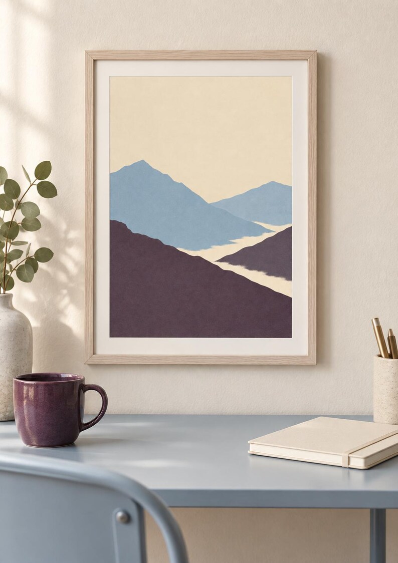 May include: A framed wall art print featuring a layered mountain landscape illustration. The artwork displays a pale cream sky above light blue mountain peaks, with dark purple foreground slopes and a winding white path through the center.