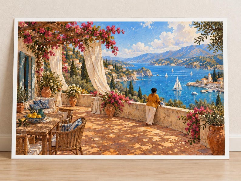 May include: A framed wall art print depicting a sunlit Mediterranean terrace with a stone wall, wicker furniture, and a bowl of lemons. A person in a yellow shirt stands by the wall overlooking a blue bay with sailboats, mountains, and pink flowers.