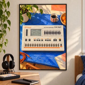 May include: A framed wall art print featuring a vintage Roland TR-707 Rhythm Composer drum machine. The device is off-white with orange accents, a digital display, and multiple sliders and buttons, set against a vibrant blue tabletop background.