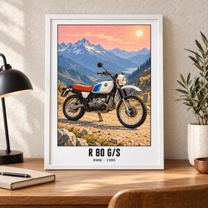 Pu&ograve; includere: Una stampa artistica incorniciata raffigurante una moto BMW R 80 G/S bianca con sella arancione, parcheggiata su un sentiero roccioso con sfondo di montagne innevate al tramonto. Il testo R 80 G/S e BMW 1980 &egrave; stampato in basso nell'immagine.
