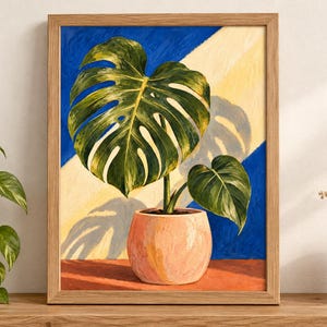 Puede incluir: Un cuadro enmarcado de una planta monstera verde en una maceta color melocot&oacute;n. El fondo presenta una divisi&oacute;n diagonal de azul intenso y amarillo p&aacute;lido, creando una sombra de las grandes hojas divididas sobre la secci&oacute;n amarilla de la pared.