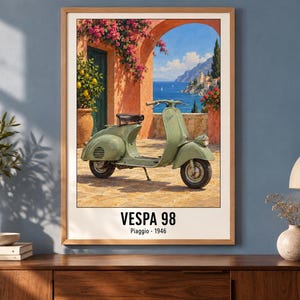 Pu&ograve; includere: Una stampa artistica incorniciata raffigurante uno scooter Vespa 98 verde salvia parcheggiato su un patio in pietra. Lo sfondo mostra una scena costiera mediterranea con un arco arancione, fiori rosa e il mare blu. Il testo recita VESPA 98 Piaggio 1946.