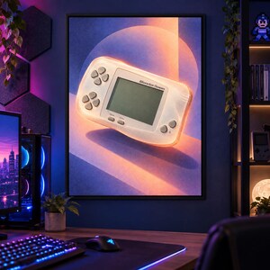 Pu&ograve; includere: Una stampa artistica da parete incorniciata raffigurante una console di gioco portatile WonderSwan bianca traslucida. La console &egrave; centrata su uno sfondo sfumato blu e arancione con un elemento grafico circolare, che mette in risalto i tasti.