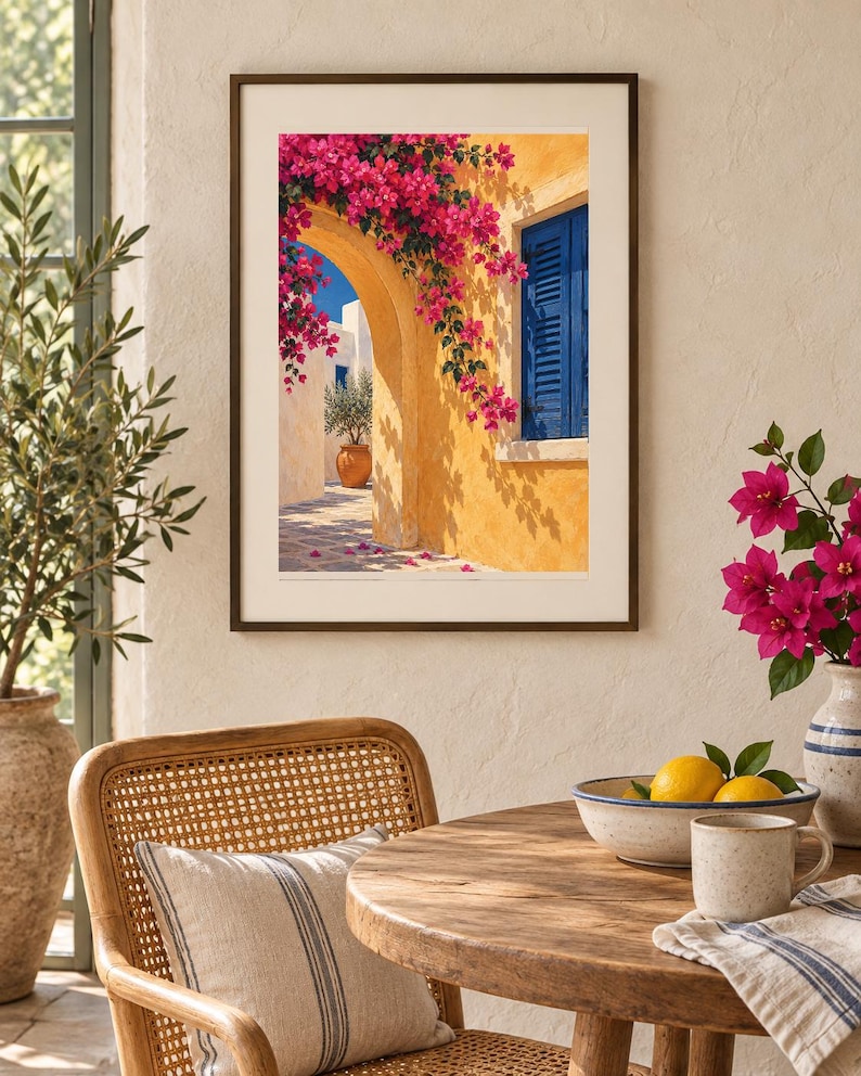 May include: A framed wall art print depicting a Mediterranean scene with a yellow stucco wall, a bright blue shuttered window, and vibrant pink bougainvillea flowers cascading over a stone archway, set in a dark brown frame with a white mat.