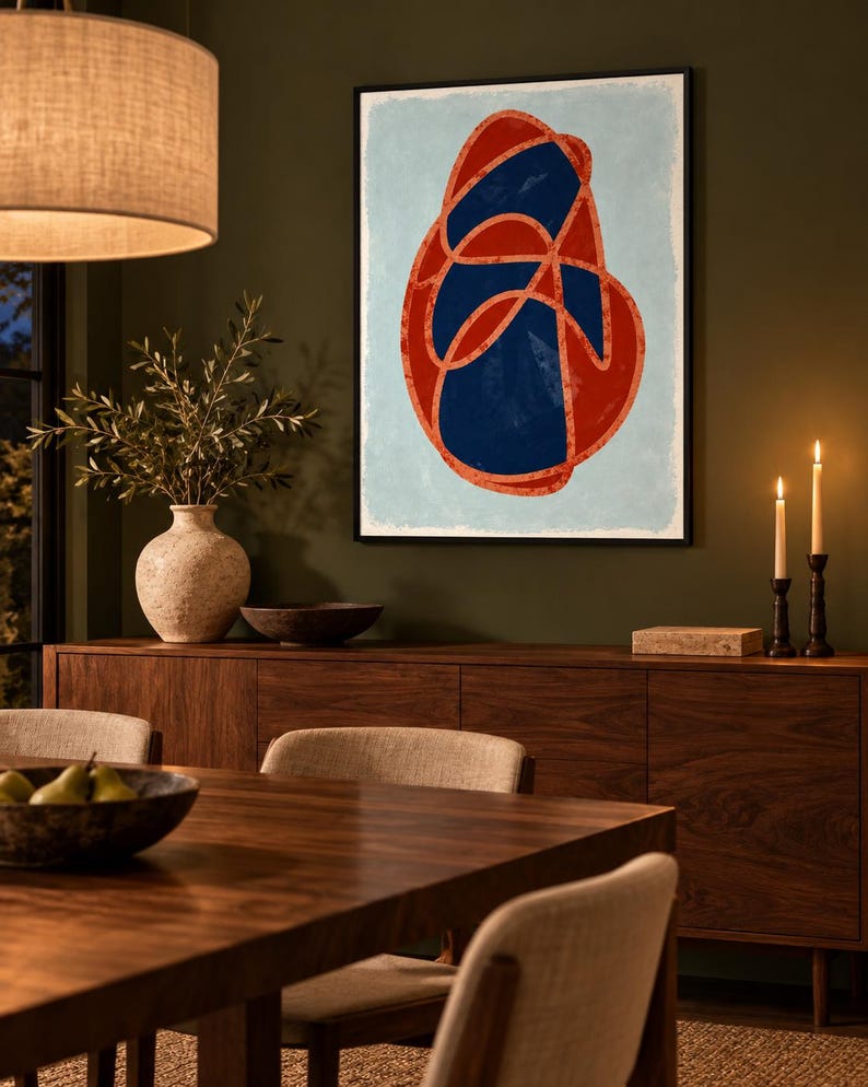 May include: A framed wall art print featuring an abstract composition with a large, irregular red and dark blue intertwined shape centered on a light blue background. The artwork is enclosed in a thin black frame and displayed on a wall.