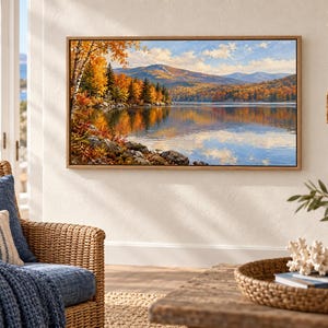 Pode incluir: Uma pintura de paisagem retangular numa moldura de madeira clara que retrata um lago sereno rodeado por folhagem de outono em tons de laranja, amarelo e vermelho. A cena apresenta um corpo de &aacute;gua calmo que reflete as &aacute;rvores e montanhas.