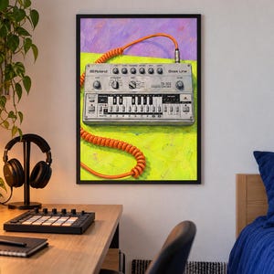 May include: A framed wall art print featuring a silver Roland TB-303 Bass Line synthesizer with a bright orange coiled cable. The synthesizer is set against a vibrant background of lime green and purple, showcasing its knobs, keys, and text.