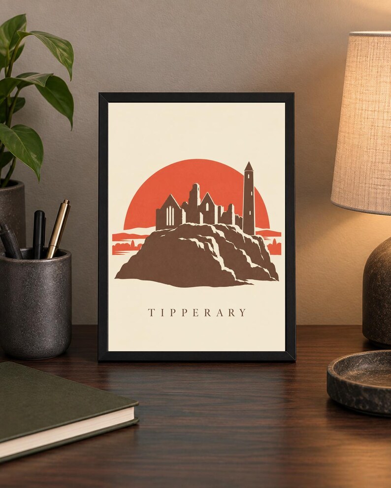 May include: A framed art print featuring a stylized illustration of the Rock of Cashel in Tipperary, Ireland. The design shows a brown stone castle silhouette against a large orange sun on a cream background, with the word TIPPERARY printed below.