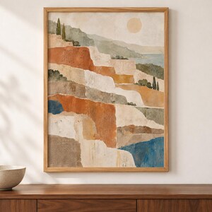 Op de afbeelding: Een ingelijste verticale kunstprint met een gelaagd landschap van terrasvormige kliffen in tinten terracotta, beige en cr&egrave;me. De sc&egrave;ne bevat kleine groene bomen, een bleke zon in een zachte lucht en vlakken van diepblauw water onderaan.