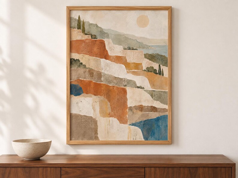 Op de afbeelding: Een ingelijste verticale kunstprint met een gelaagd landschap van terrasvormige kliffen in tinten terracotta, beige en cr&egrave;me. De sc&egrave;ne bevat kleine groene bomen, een bleke zon in een zachte lucht en vlakken van diepblauw water onderaan.