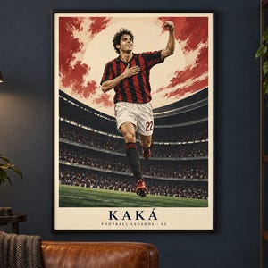 May include: A framed vertical poster featuring a soccer player in a red and black striped jersey and white shorts with the number 22, celebrating on a field. The background shows a stadium and a large sun. Text at the bottom reads KAK&Aacute; FOOTBALL LEGENDS - 03.