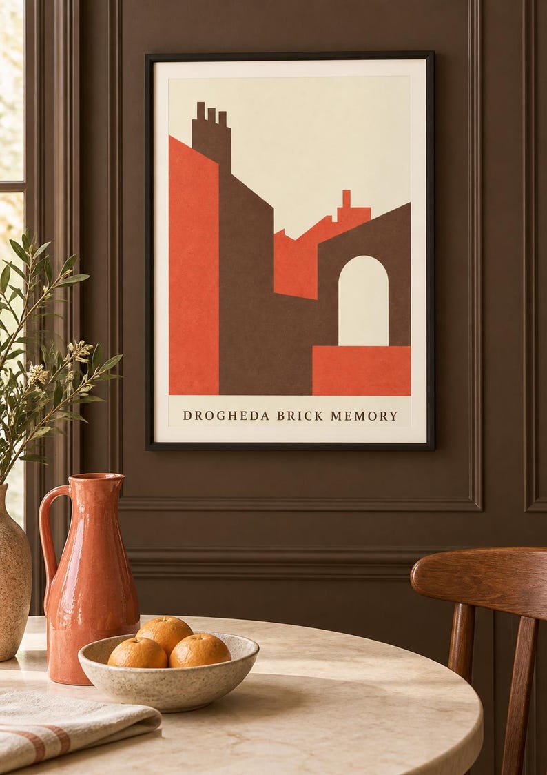 K&ouml;nnte beinhalten: Ein gerahmter Kunstdruck mit dem Titel DROGHEDA BRICK MEMORY, der eine geometrische Illustration von Geb&auml;uden in Dunkelbraun, gebranntem Orange und Creme zeigt. Das Bild zeigt stilisierte D&auml;cher, Schornsteine und einen Torbogen.