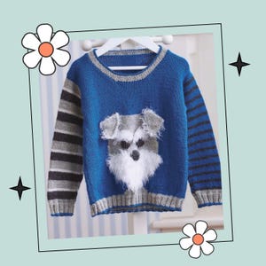 Pode incluir: Um suéter de tricô azul com um padrão de listras cinza e pretas nas mangas. O suéter tem um rosto de cachorro de tricô branco e cinza na frente.