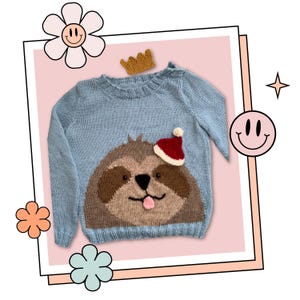 Può includere: Un maglione di lana blu chiaro con un bradipo marrone che indossa un cappello di Babbo Natale rosso sul davanti. Il maglione ha un collo rotondo e maniche lunghe.