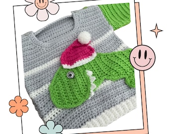 May include: A gray and white striped crocheted sweater with a green dinosaur applique wearing a pink and white crocheted Santa hat.