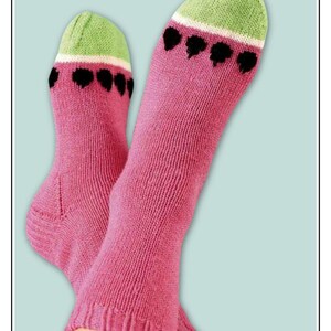 May include: A pair of pink knitted socks with a watermelon design. The toe and heel are green with a white stripe, and black heart-shaped seeds are embroidered on the pink body of the socks. The socks are displayed against a light blue background.