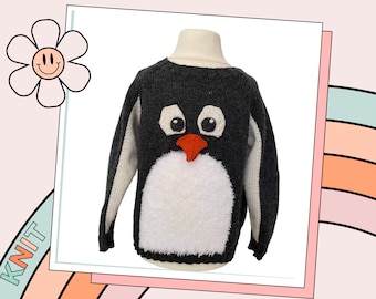 May include: A grey knitted jumper with a white penguin design. The penguin has black eyes, an orange beak, and a white fluffy tummy.