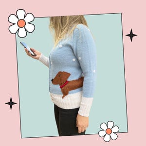 May include: A light blue knitted cardigan with white polka dots and a brown dachshund applique. The cardigan has a white trim at the bottom and cuffs.