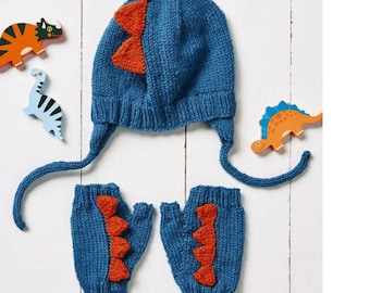 May include: A blue knitted dinosaur-themed hat with ear flaps and matching fingerless gloves. The hat and gloves feature orange dinosaur spikes. Wooden dinosaur toys are scattered around the set.