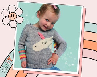 May include: A gray knitted sweater with a white unicorn applique. The unicorn has pink and white yarn for the horn and mane. The sweater has rainbow stripes on the cuffs.