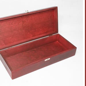 May include: A red wooden box with a hinged lid and a silver latch. The box is open and empty.