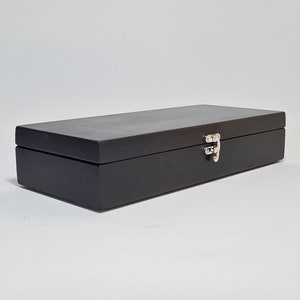 May include: A black wooden box with a silver latch. The box is closed and has a smooth, polished finish.