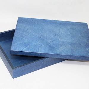 May include: A blue wooden box with a lid. The box is made of a light blue wood with a dark blue trim. The lid is slightly ajar.
