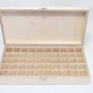 Könnte beinhalten: Eine Holzkiste mit einem Scharnierdeckel und einem Riegel. Die Kiste hat 36 Fächer im Inneren, perfekt zum Aufbewahren von kleinen Gegenständen.