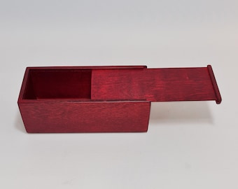 May include: A small, rectangular wooden box with a hinged lid. The box is made of a dark red wood and has a smooth finish.