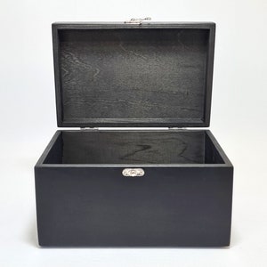 May include: A black wooden box with a hinged lid and silver metal clasps. The box is open and empty.