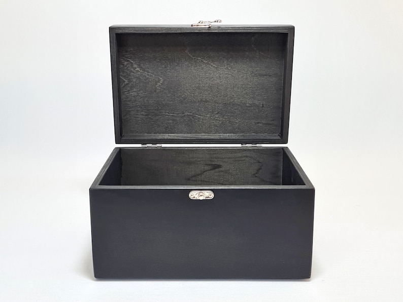 May include: A black wooden box with a hinged lid and silver metal clasps. The box is open and empty.