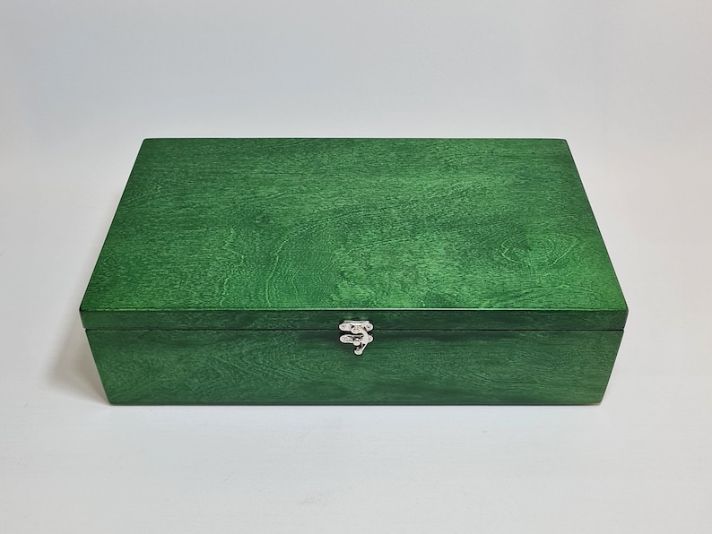 May include: A green wooden box with a hinged lid and a silver latch. The box is made of wood with a smooth finish.