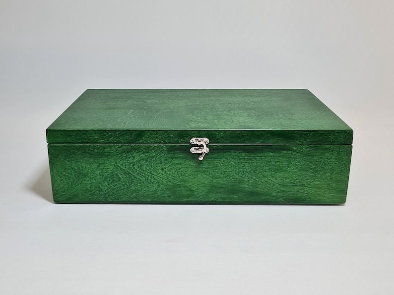 May include: A dark green wooden box with a silver latch. The box has a smooth, polished finish.