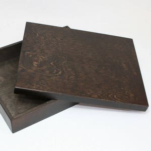 May include: A dark brown wooden box with a lid. The lid is open and the box is empty.