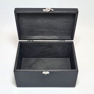 May include: A black wooden box with a hinged lid and a silver latch. The box is empty and open.