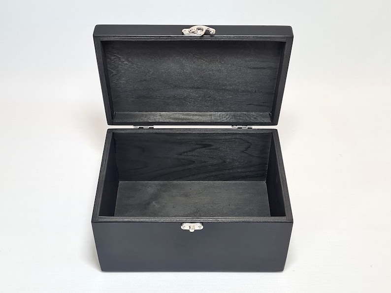 May include: A black wooden box with a hinged lid and a silver latch. The box is empty and open.