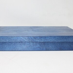 May include: A blue wooden box with a lid. The box is made of a light wood and has a smooth finish.
