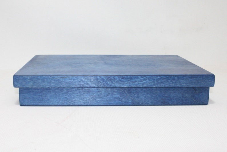 May include: A blue wooden box with a lid. The box is made of a light wood and has a smooth finish.