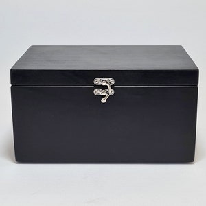 May include: A black wooden box with a silver latch. The box is closed.