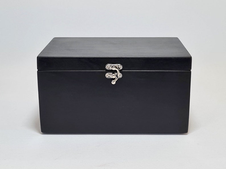 May include: A black wooden box with a silver latch. The box is closed.