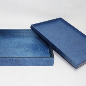 May include: A blue wooden box with a lid. The box is made of wood and has a smooth finish. The lid is slightly ajar, revealing the interior of the box.