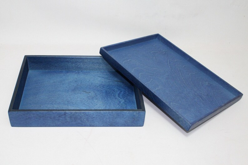 May include: A blue wooden box with a lid. The box is made of wood and has a smooth finish. The lid is slightly ajar, revealing the interior of the box.