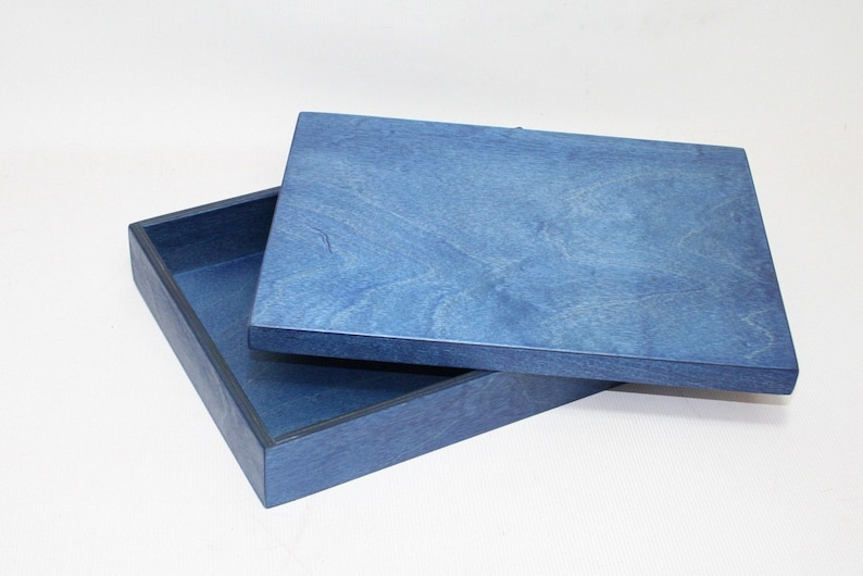 May include: A blue wooden box with a lid. The box is made of a light blue wood with a dark blue trim. The lid is slightly ajar.