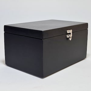 May include: A black wooden box with a hinged lid and a silver latch. The box is closed.