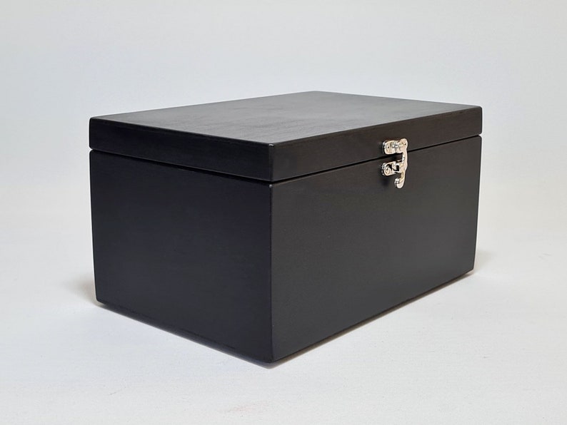 May include: A black wooden box with a hinged lid and a silver latch. The box is closed.