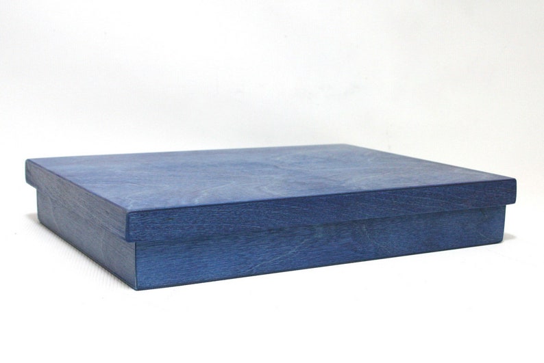 May include: A blue wooden box with a lid. The box is made of a light blue wood with a grainy texture.