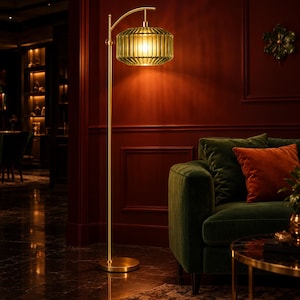 May include: A floor lamp with a slender gold-toned metal stand and a circular base. The lamp features a horizontal, ribbed, olive-green glass shade that emits a warm, glowing light, suspended from a curved arm at the top of the vertical pole.
